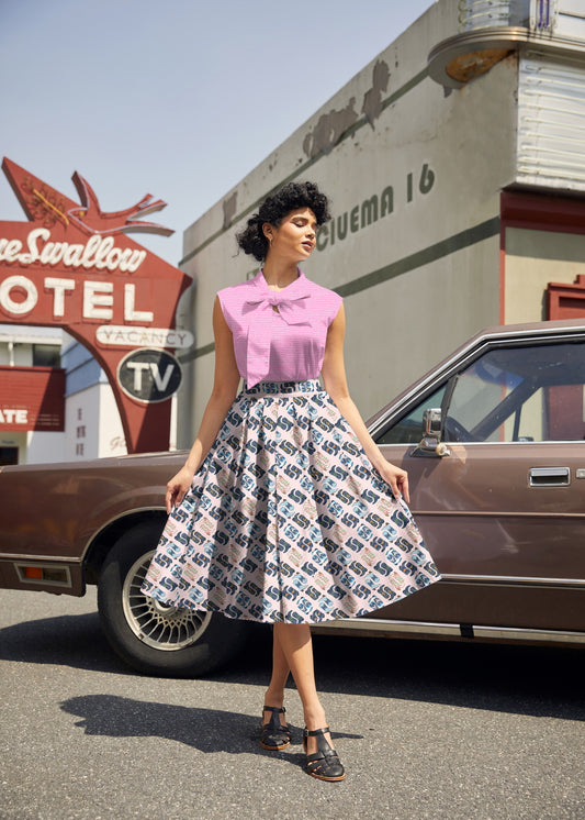 Woman in a vintage outfit standing in front of a classic car with a motel sign in the background
