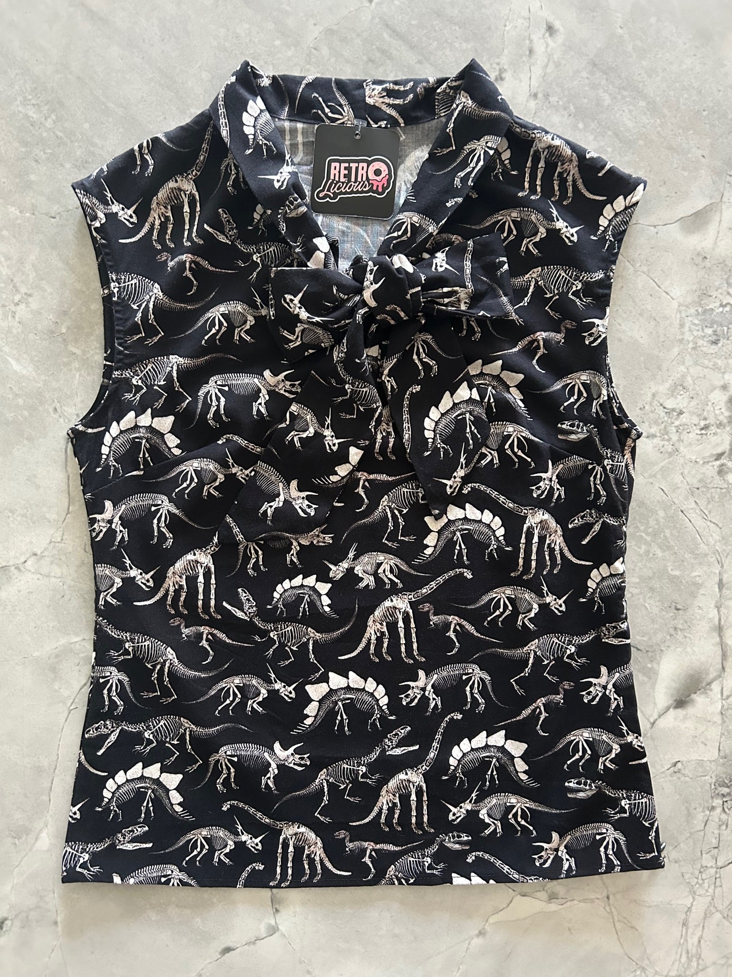 Black bow top with white dinosaur pattern on a light gray surface