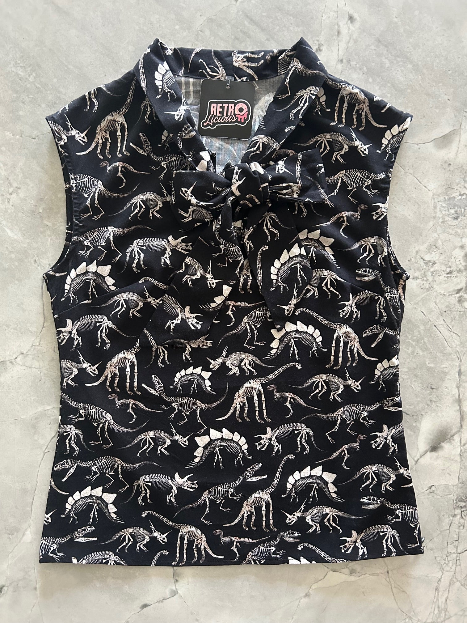 Black bow top with white dinosaur pattern on a light gray surface