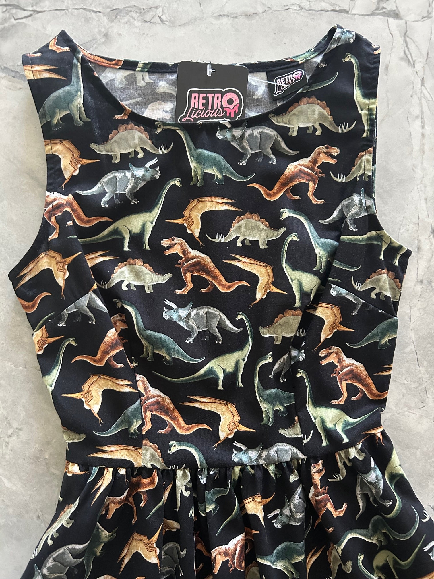Dinosaur-patterned dress on a light gray surface