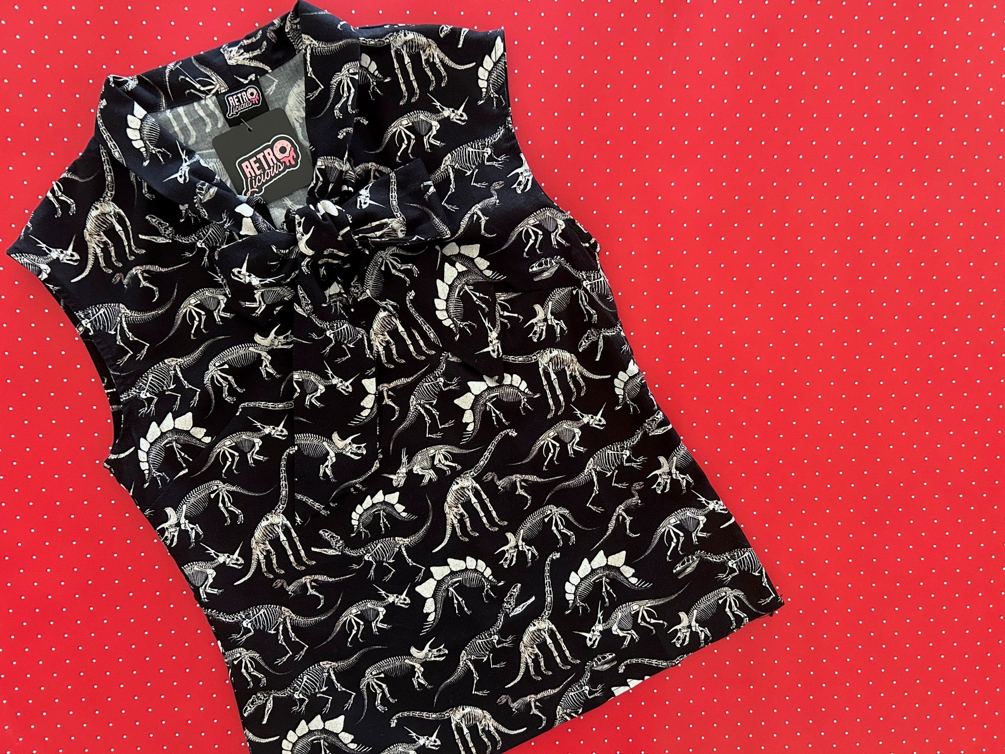 Black sleeveless top with dinosaur pattern on a red background