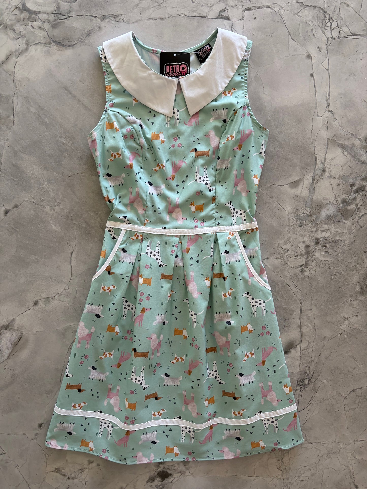 flatlay of collared dress with dog pattern on a gray surface