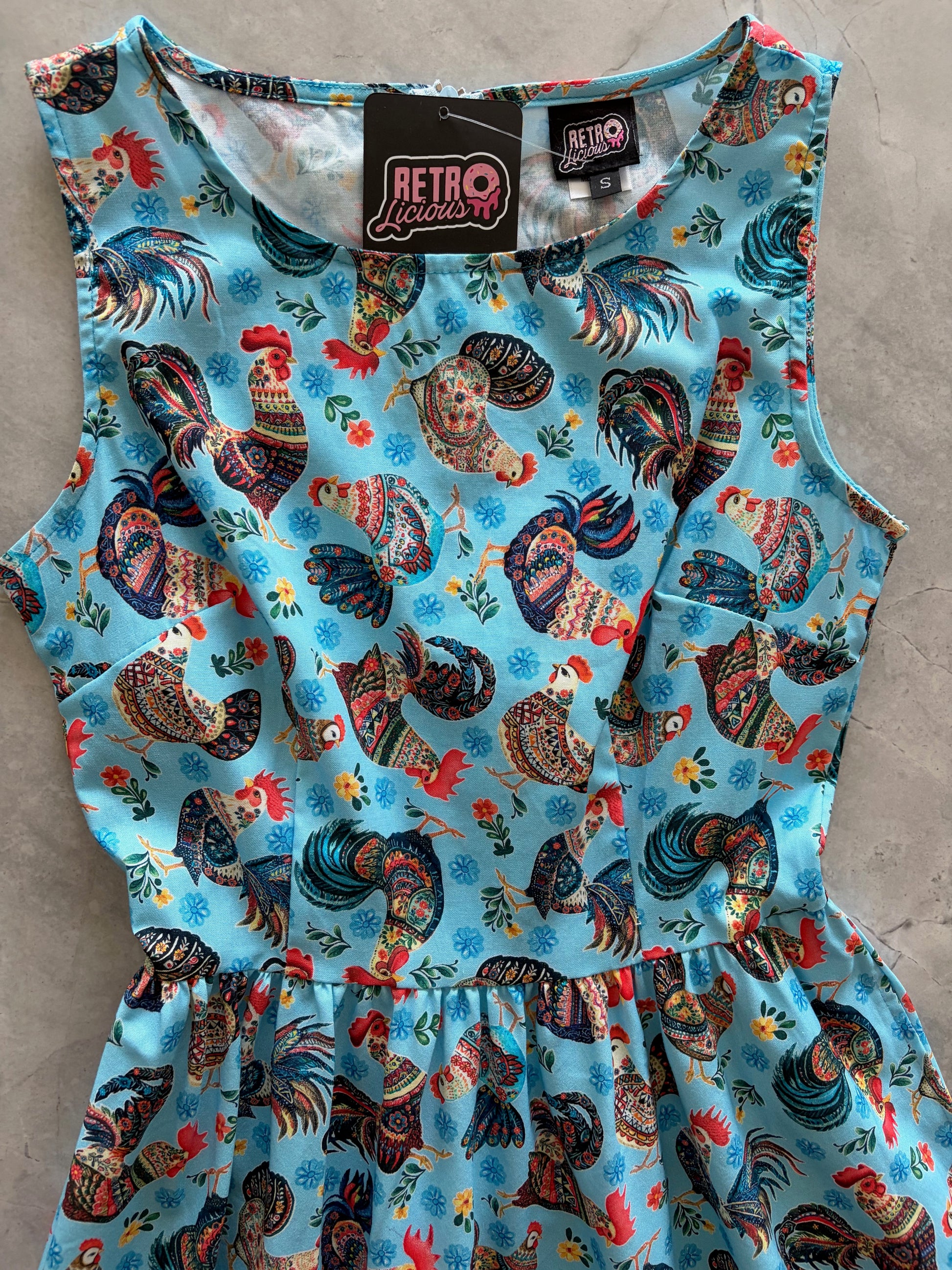 Fabric with rooster pattern on a blue background, displayed on a flat surface.