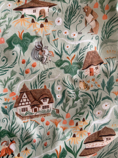 Patterned fabric with houses, trees, and animals on a light background