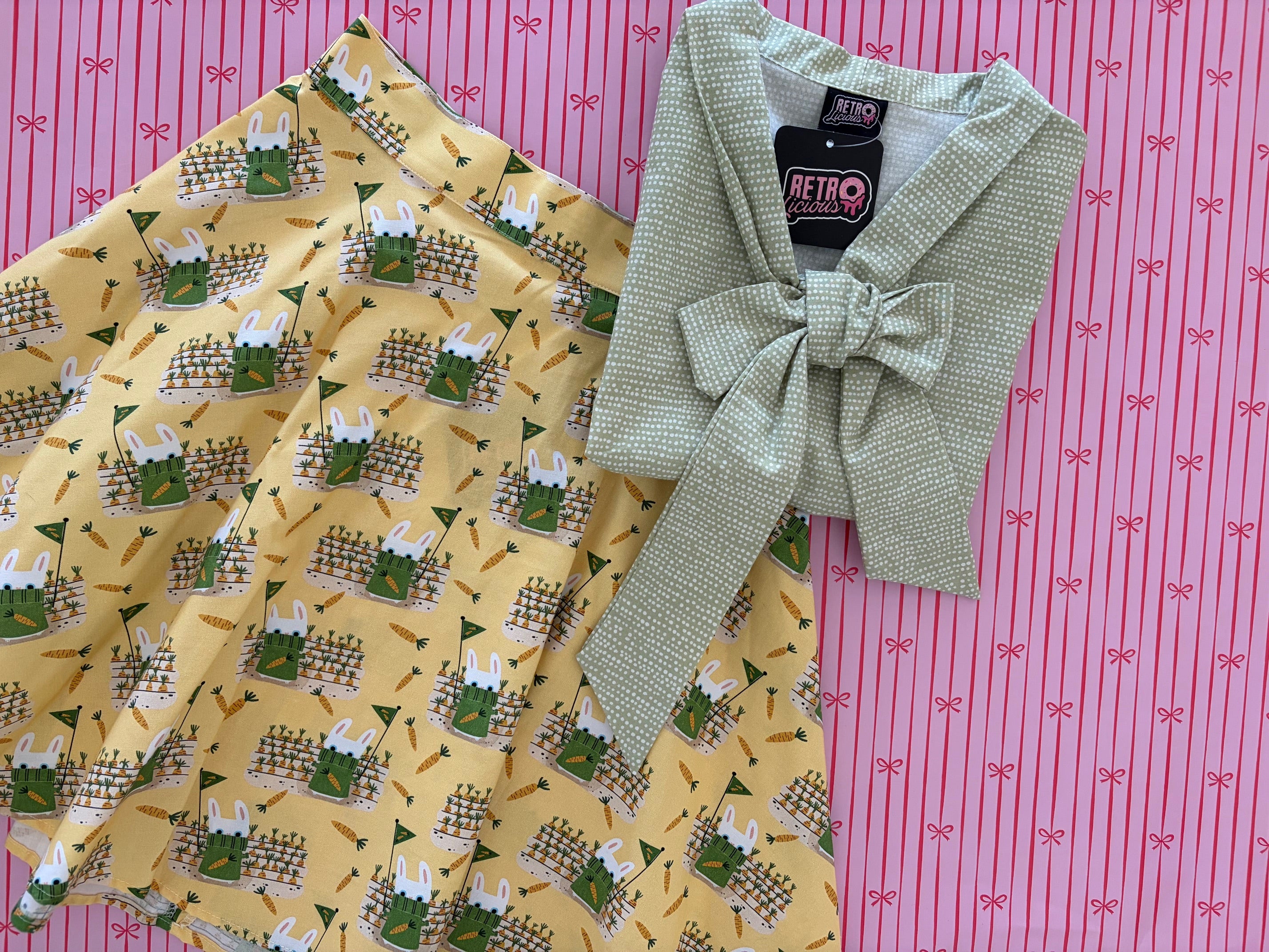 Green patterned fabric with a bow and yellow fabric with rabbit pattern on a pink background