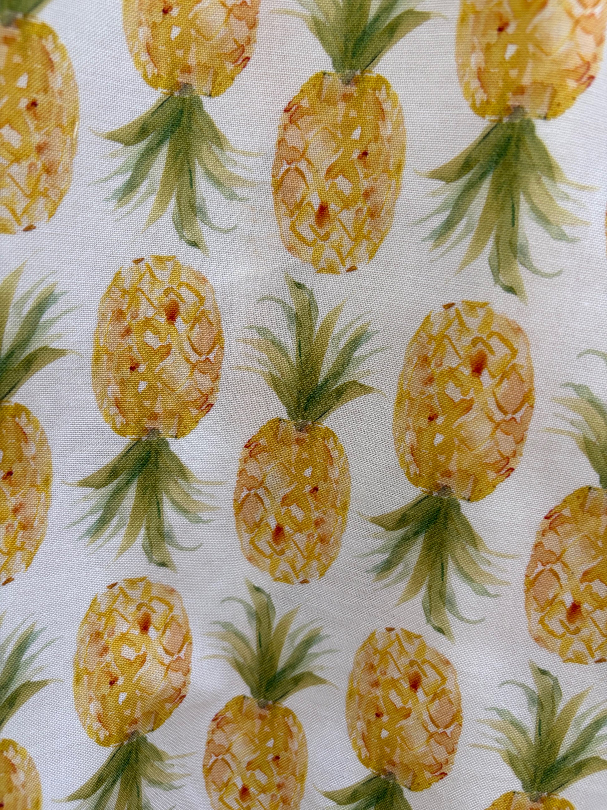 Pattern of yellow pineapples with green leaves on a white background