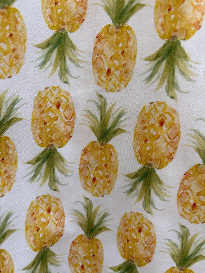 Pattern of yellow pineapples with green leaves on a white background