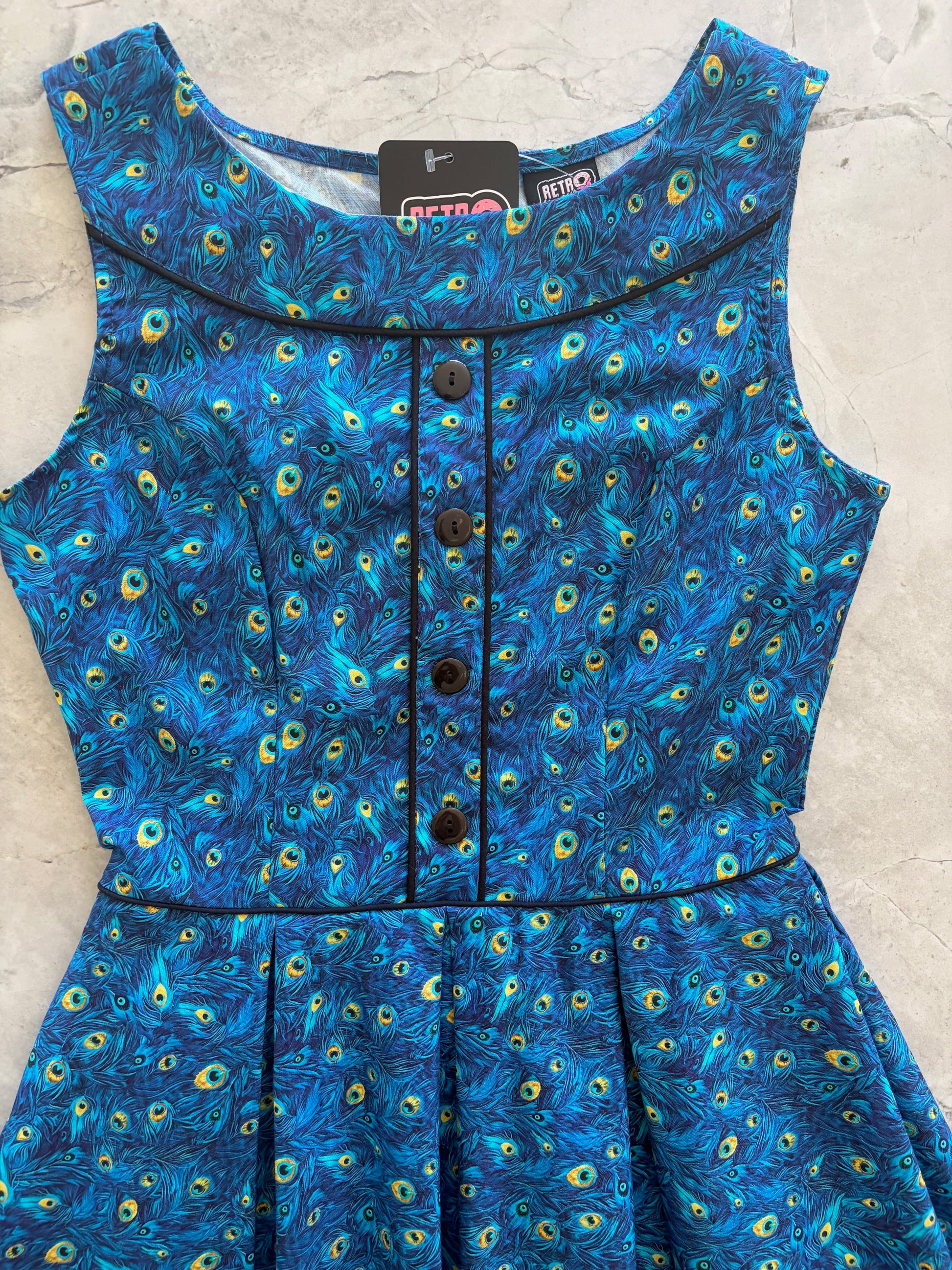 Blue peacock patterned dress on a light gray background