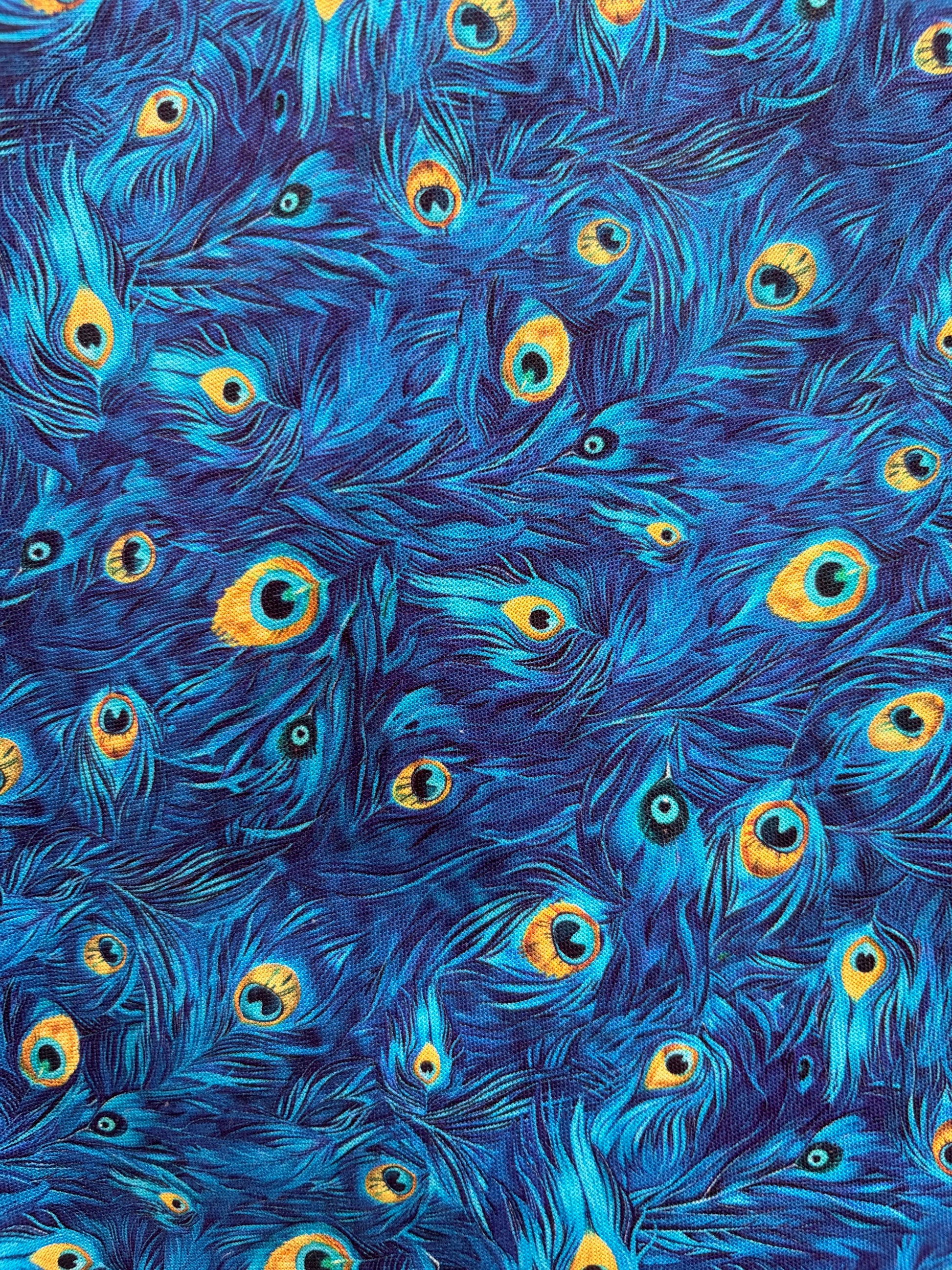 Pattern of blue peacock feathers with yellow centers on a blue background