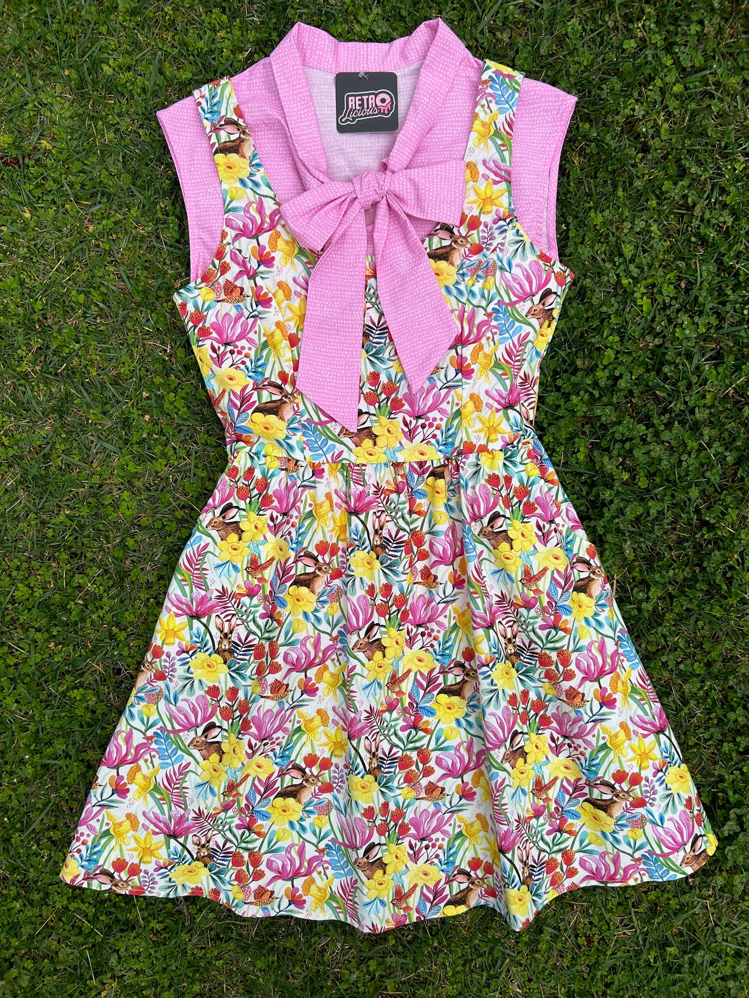 flatlay of bunny dress shown with a pink bow top on grass