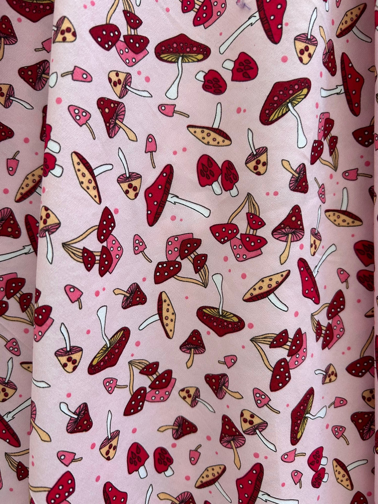 close up of toadstool print showing tossed mushrooms in reds and pink on pink background