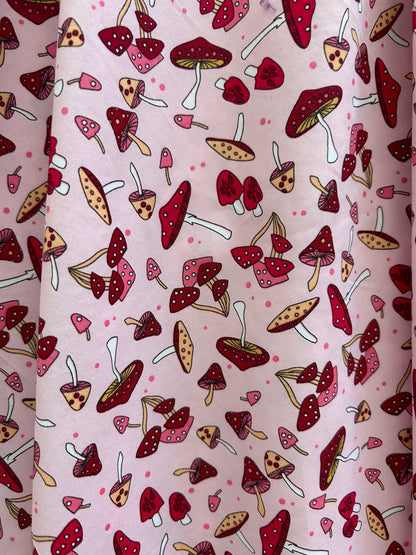 close up of toadstool print showing tossed mushrooms in reds and pink on pink background