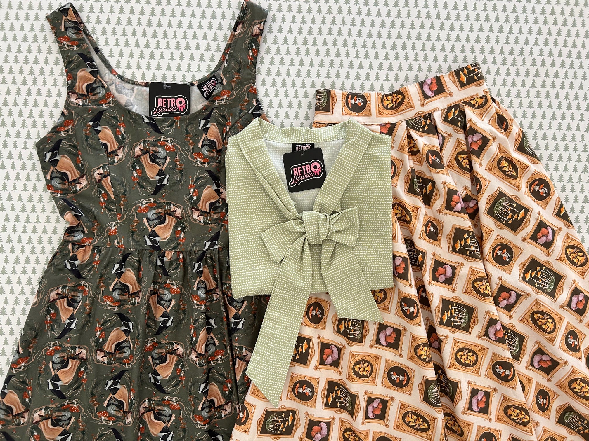 flatlay grouping of bow top in sage dots and mushroom skirt on a white background with trees