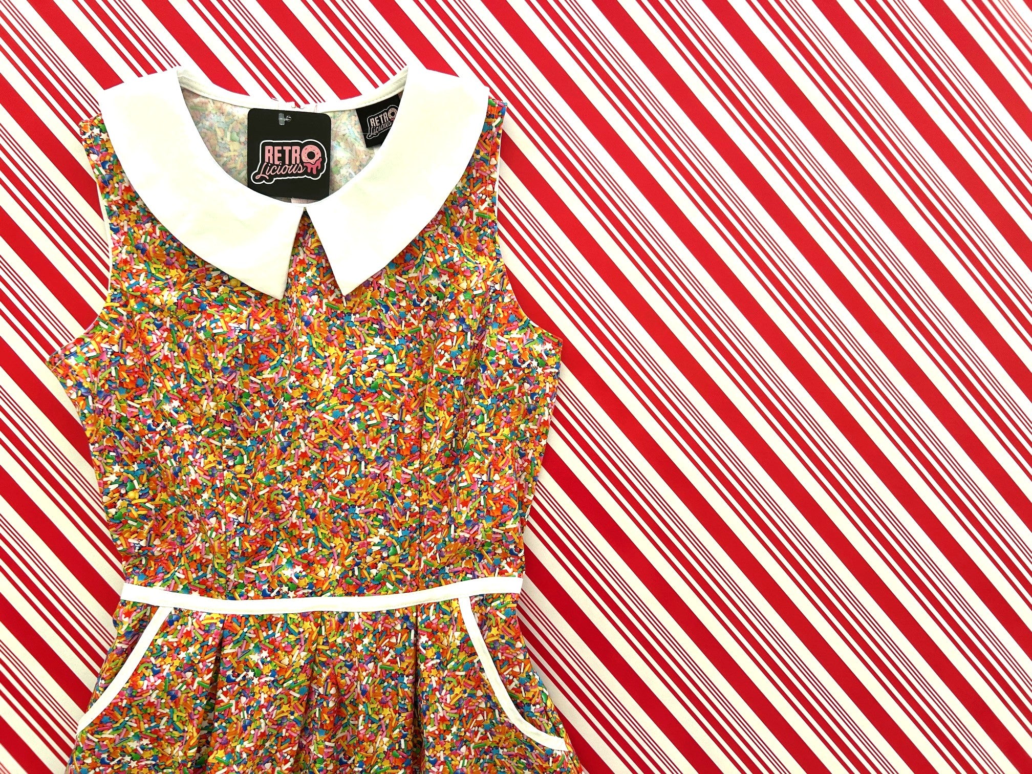Colorful confettie dress with a white collar on a red and white striped background