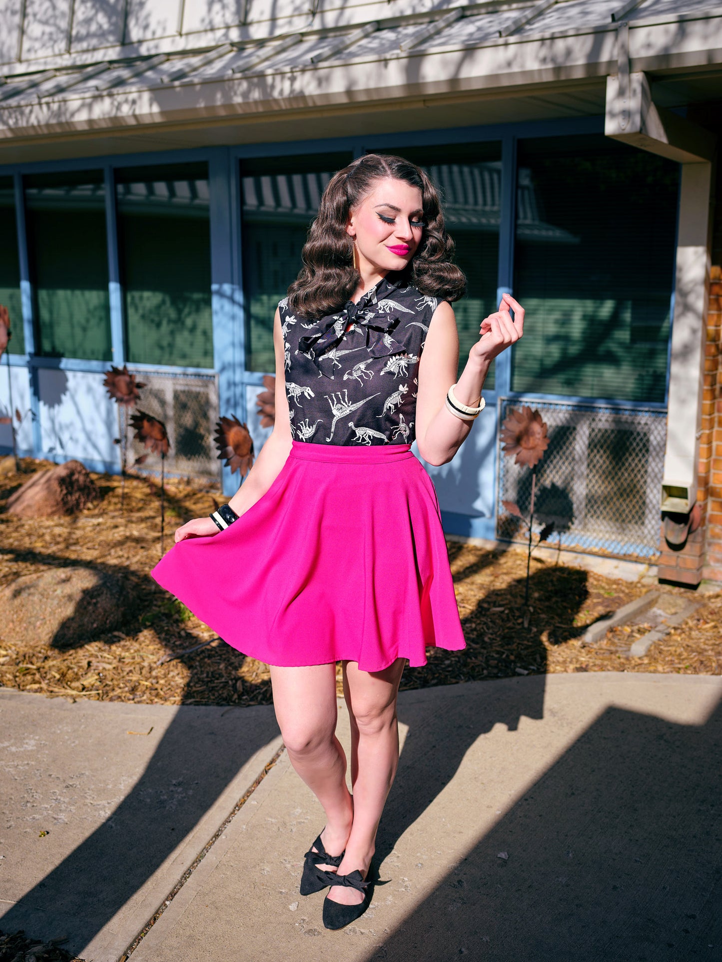a model standing outside in front of a building wearing magenta skater skirt
