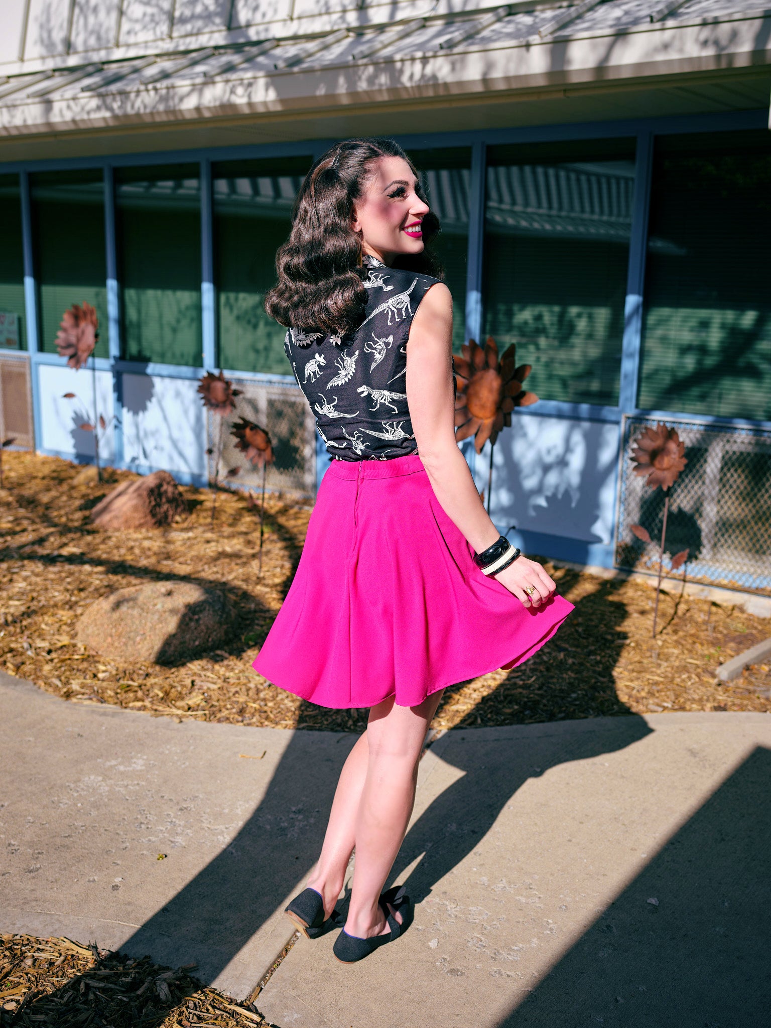 a back view of model standing outside in front of a building wearing magenta skater skirt