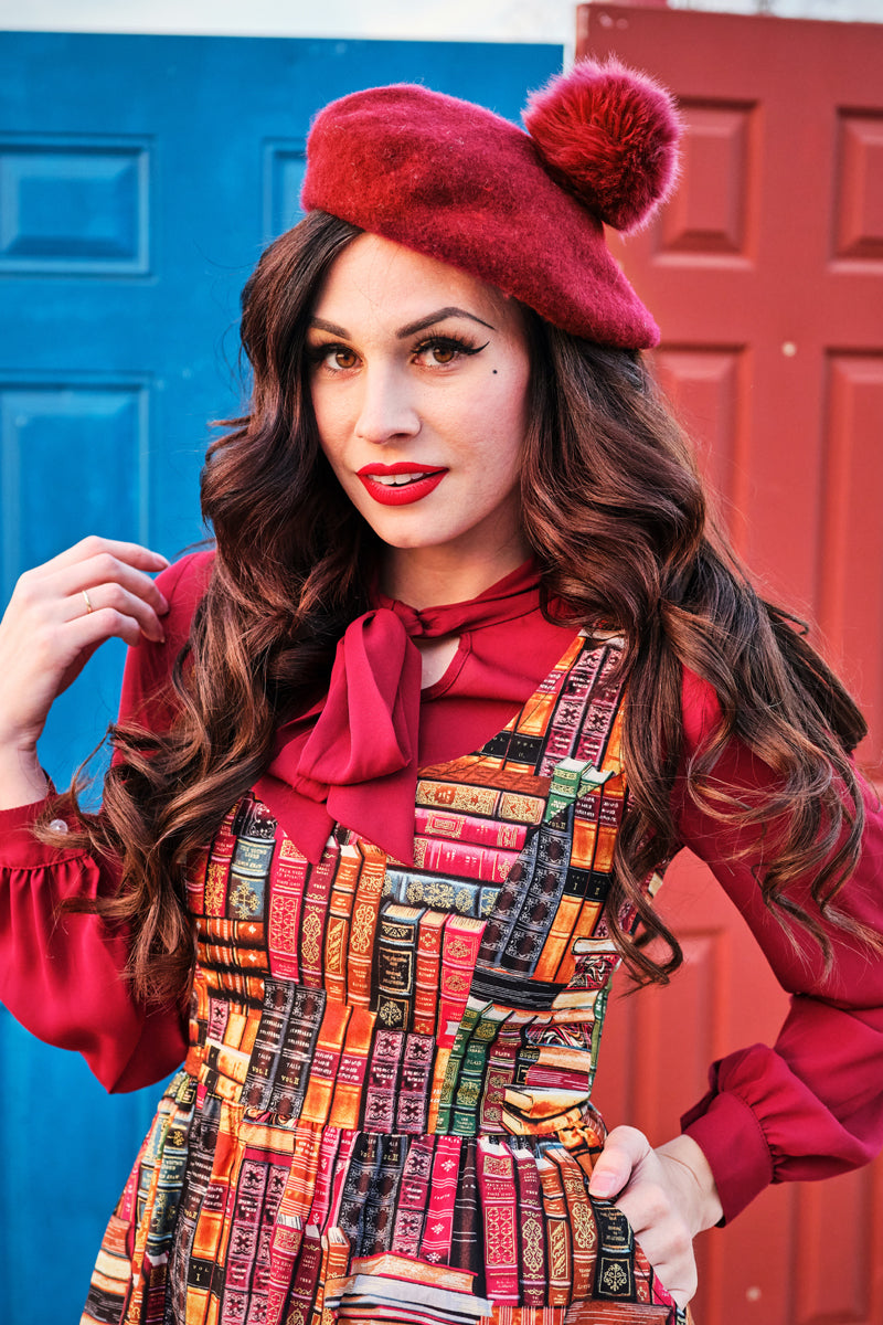 a close up of a model standing in front of doors wearing our don't judge a book by its cover fit and flare dress