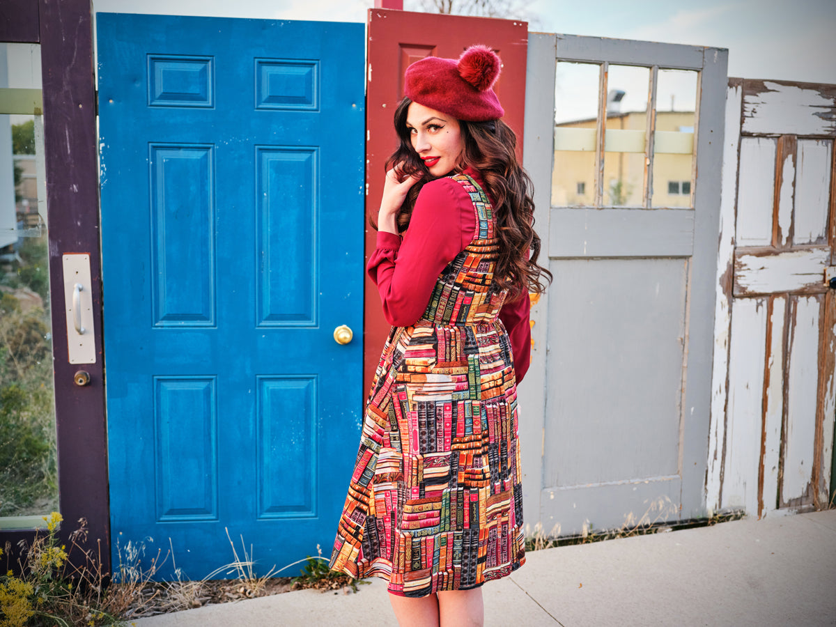 a back side of a model standing in front of doors wearing our don't judge a book by its cover fit and flare dress