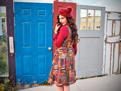 a back side of a model standing in front of doors wearing our don't judge a book by its cover fit and flare dress
