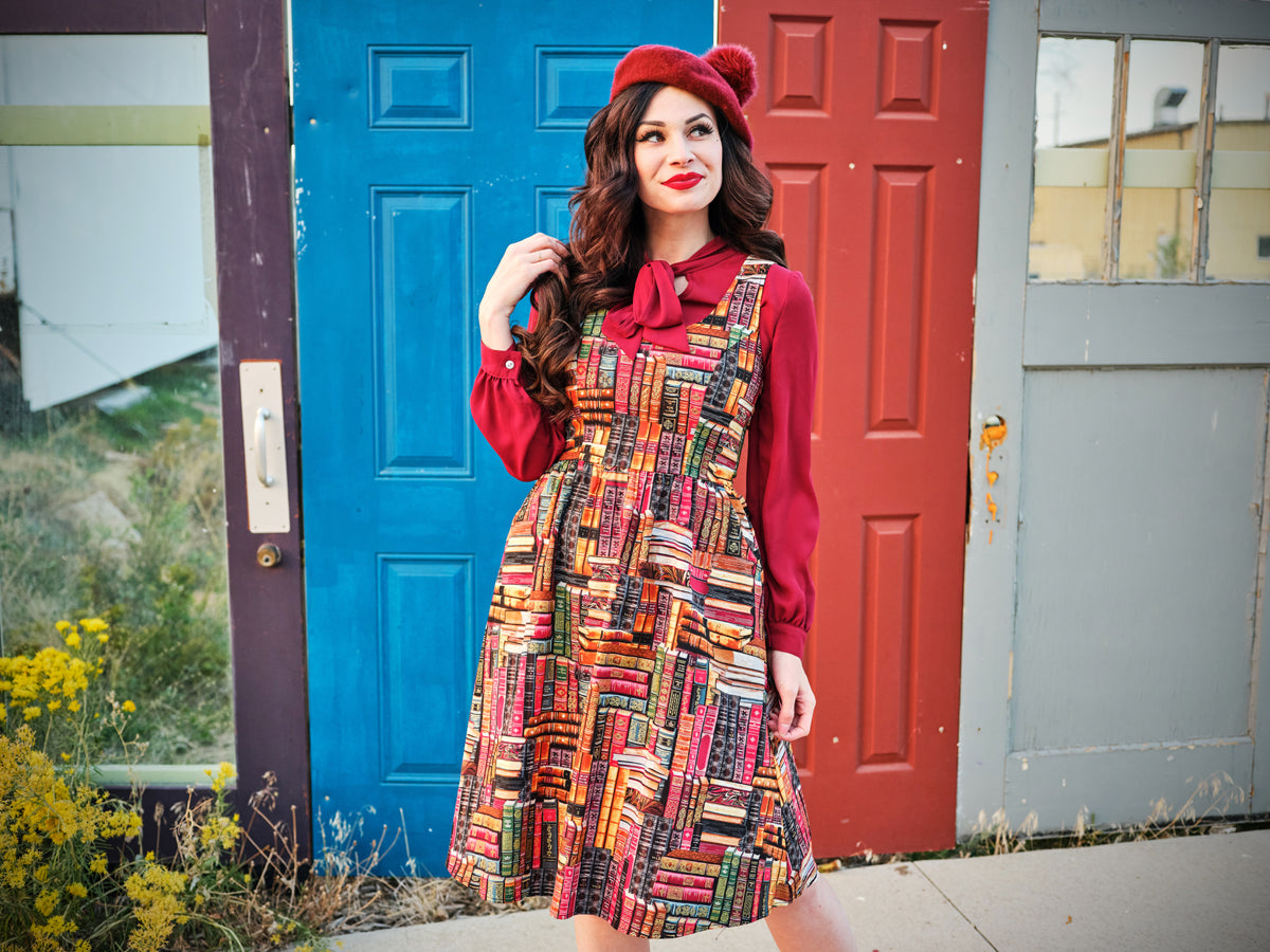 a model standing in front of doors wearing our don't judge a book by its cover fit and flare dress