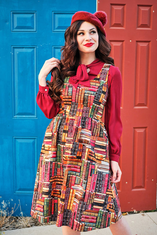 a model standing in front of doors wearing our don't judge a book by its cover fit and flare dress