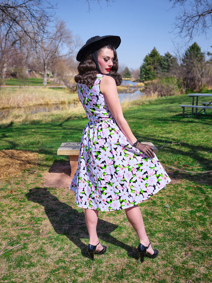 a back view of model in a park wearing magnolia midi dress and a black vintage hat