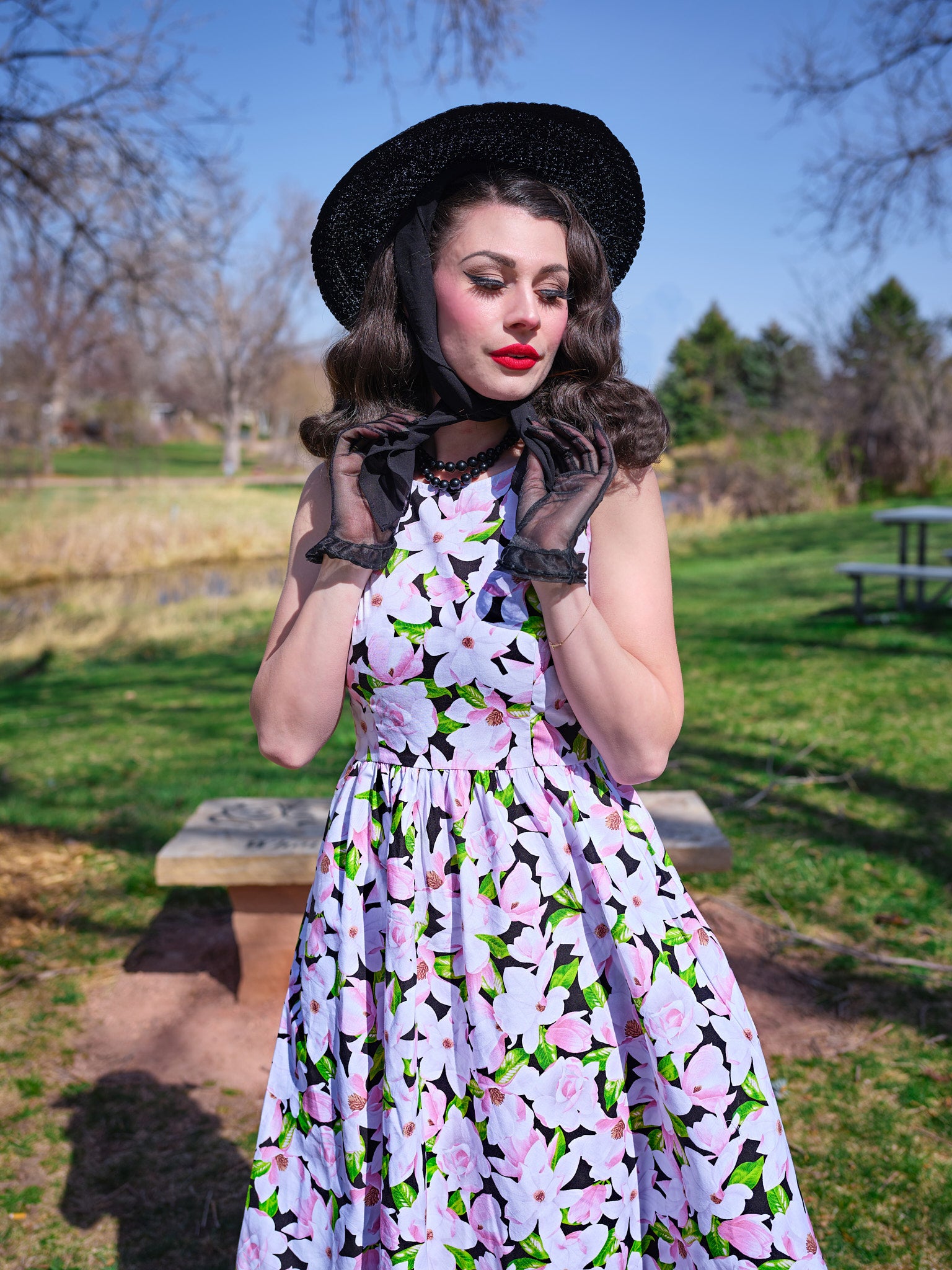 a close up of model in a park wearing magnolia midi dress and a black vintage hat
