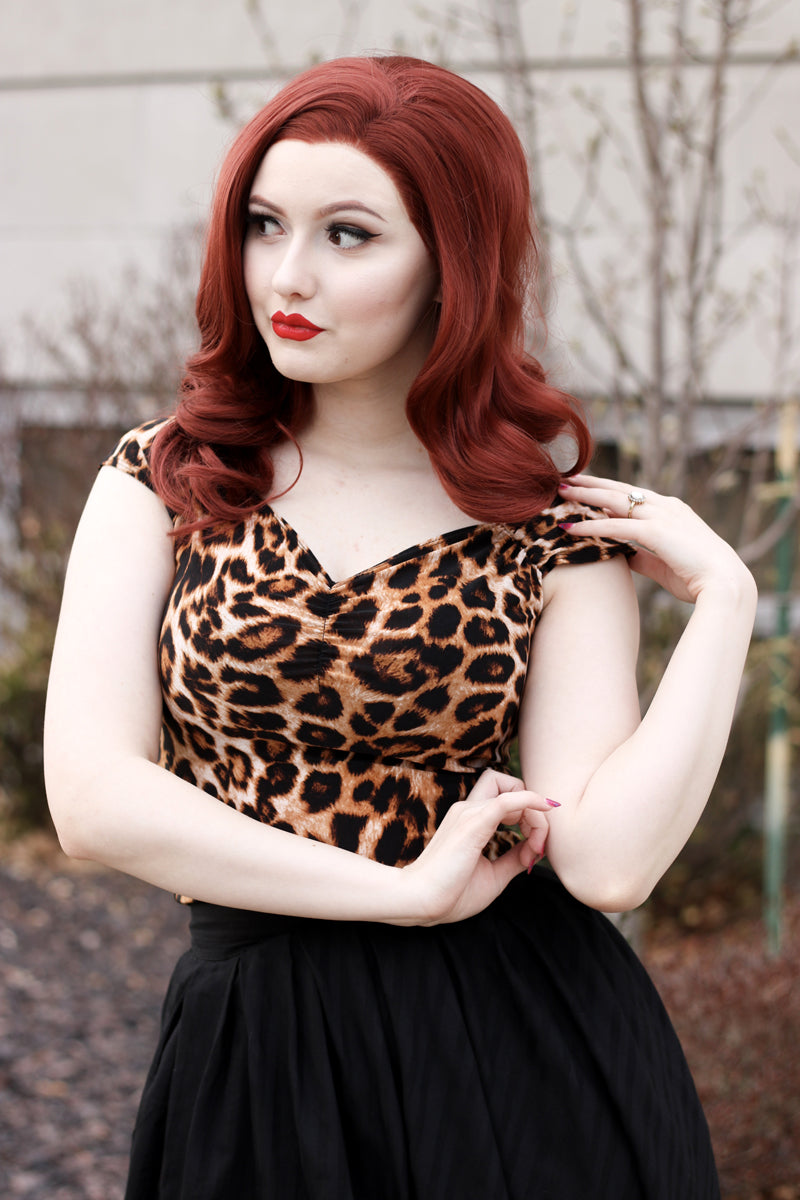 a close up of a model wearing our Leopard Isabel Top she is looking to the side and has her hand on her shoulder