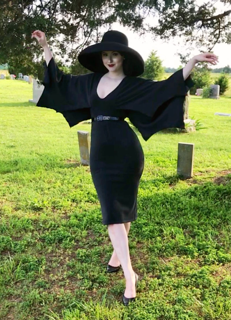 a full size image of a model wearing our bat wing Creature of the Night Wiggle Dress and her arms ar up showing the bat wings