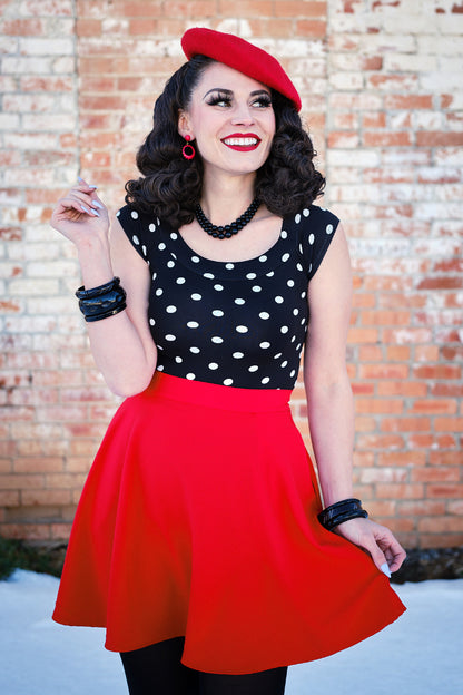 a model standing in front of a brick wall wearing red skater skirt 