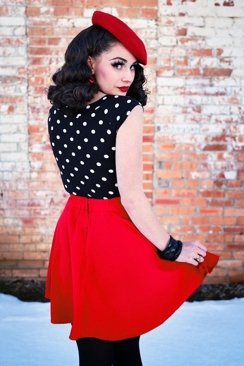 a back view of a model standing in front of a brick wall wearing red skater skirt