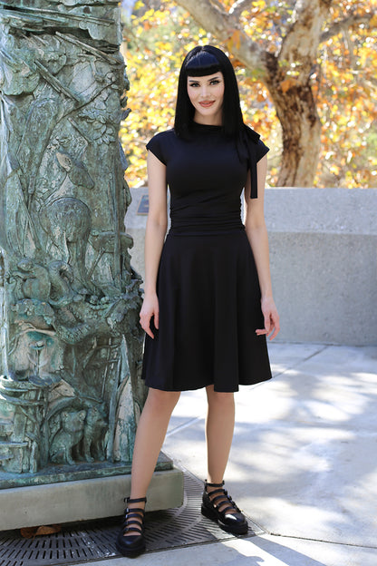 a full image of a model standing outdoors wearing the bombshell dress in black