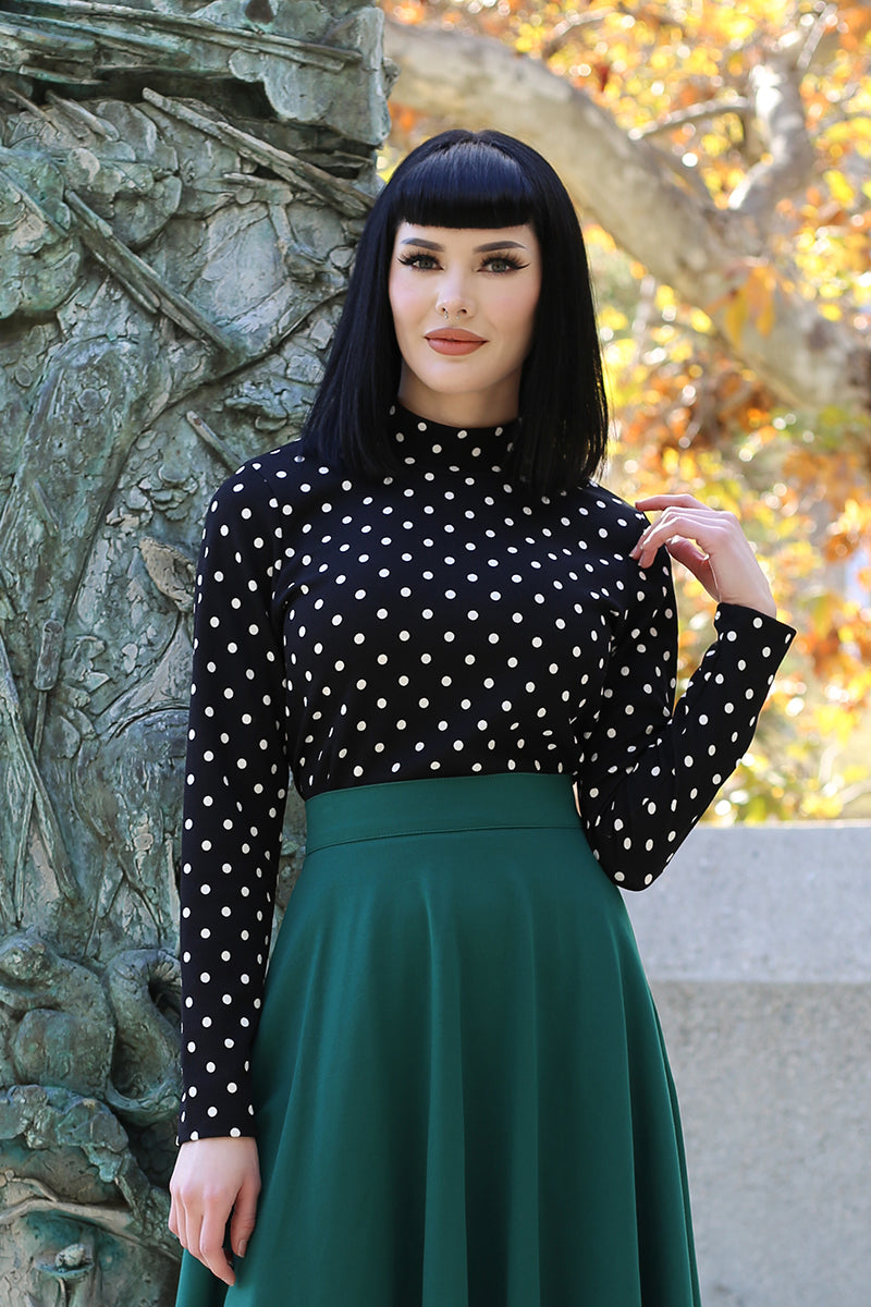 Model wearing polka dot black top while posing in the wilderness