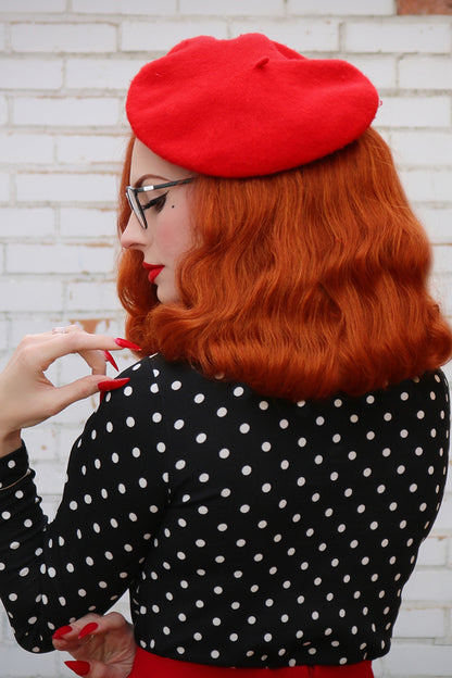Back-shot of model wearing a red beret with a retro era black long-sleeve top.