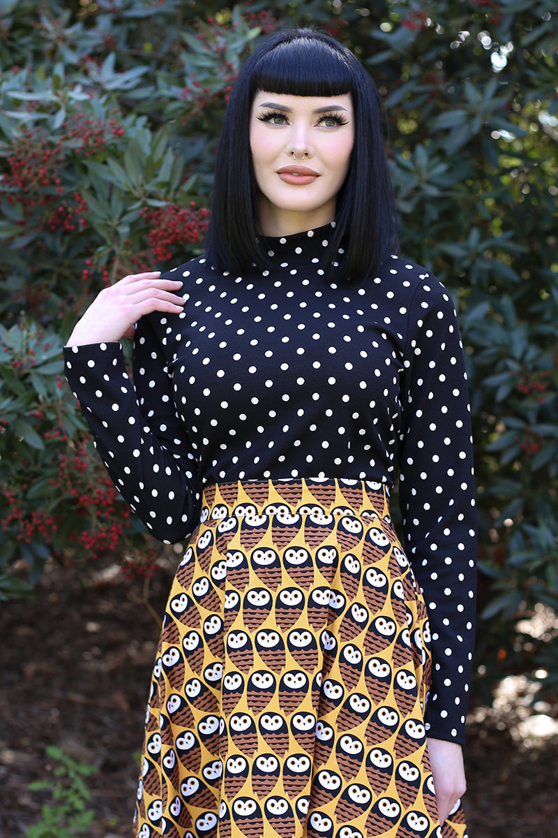 Model wearing polka dot black top while posing in the wilderness