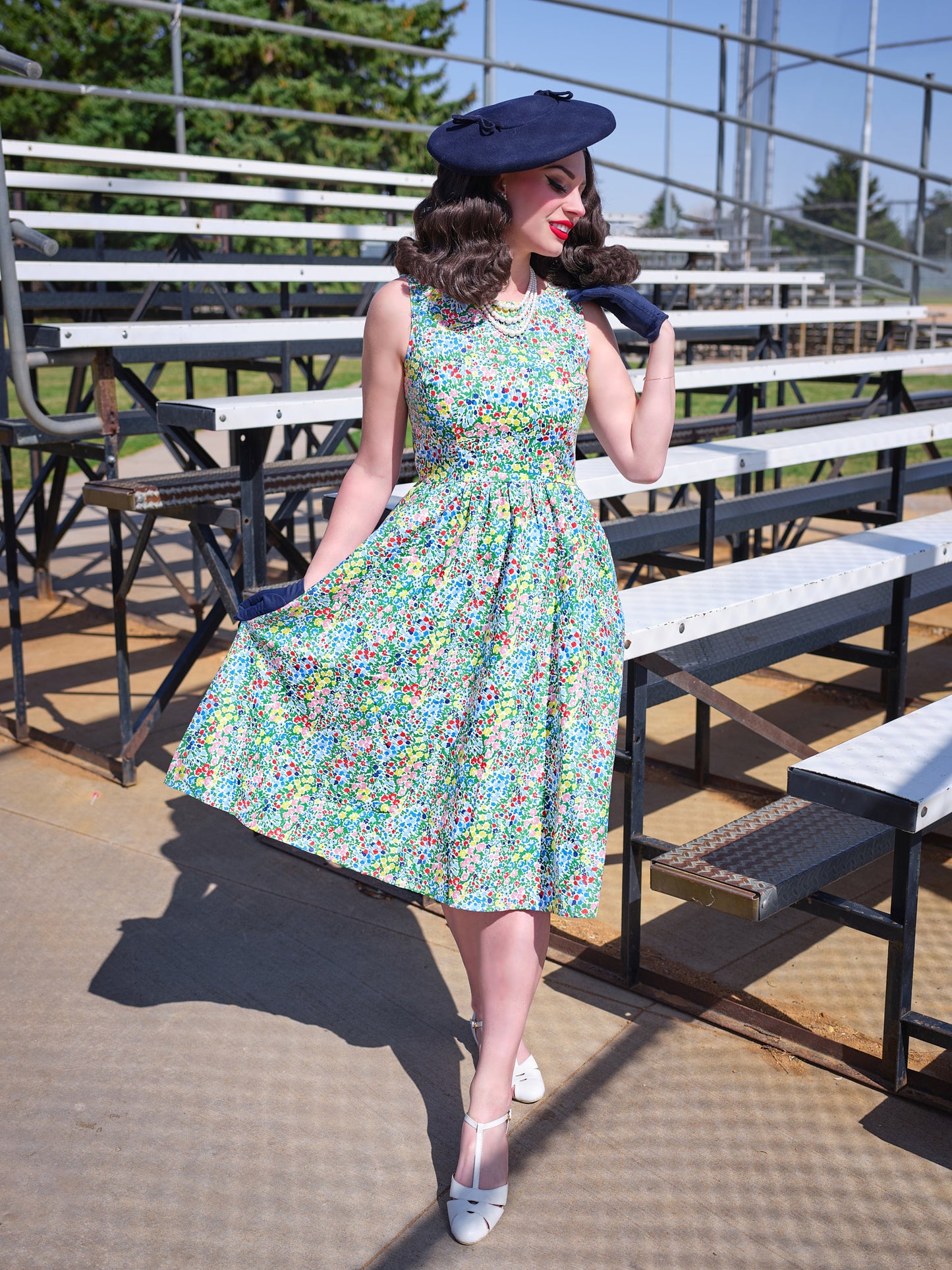 a model standing in front of bleachers wearing painted floral midi dress