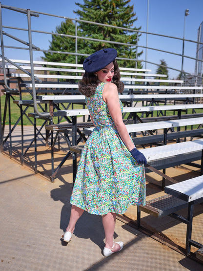 a backshot of a model standing in front of bleachers wearing painted floral midi dress