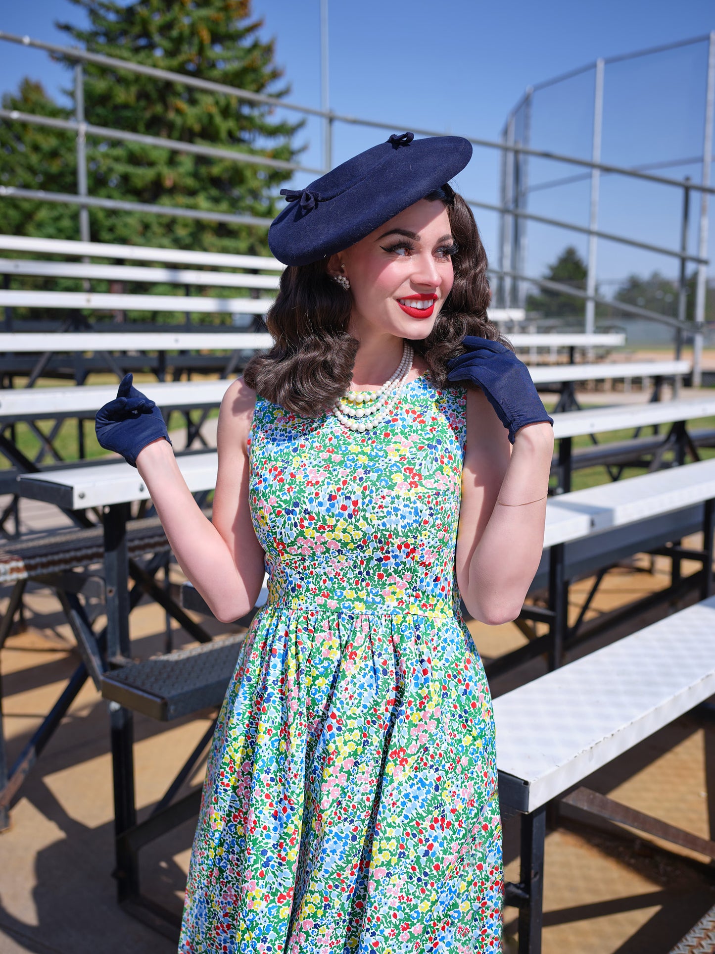 a close up of a model standing in front of bleachers wearing painted floral midi dress