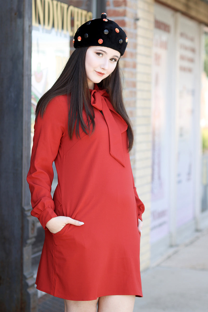 Model wearing red long sleeve dress with black hat