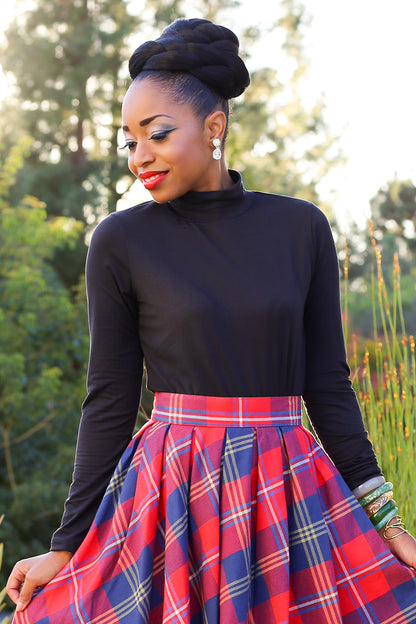 Model wearing black stretch top with red plaid skirt 