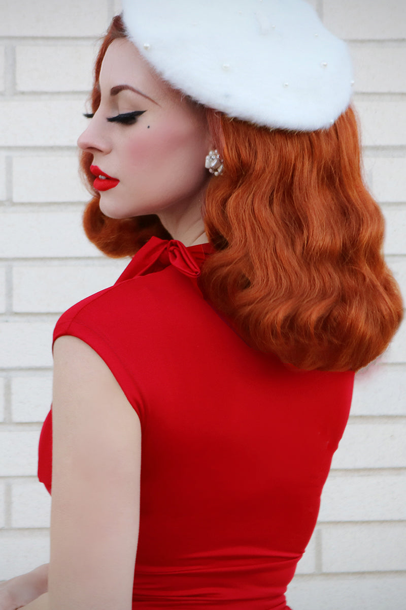 Backshot of model wearing a sleeveless red dress and white beret.