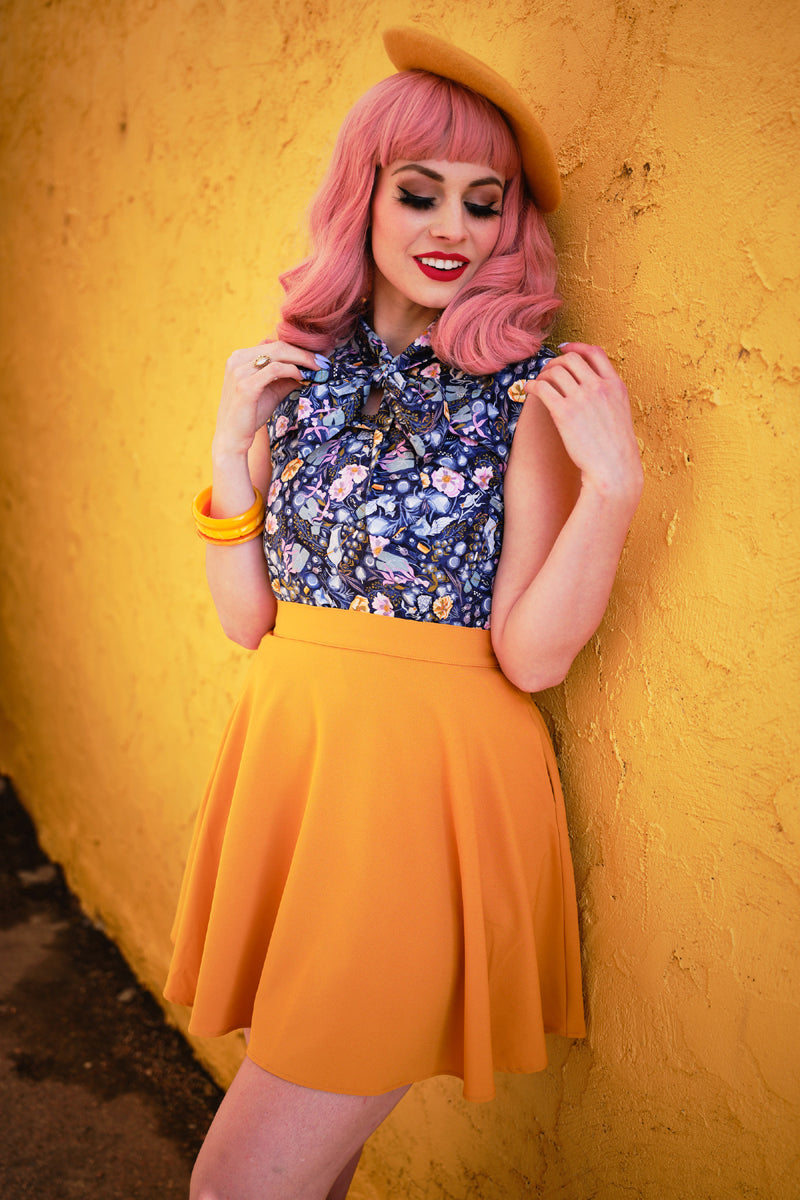 a model standing in front of a yellow wall wearing mustard skater skirt