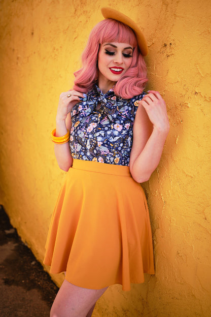 a model standing in front of a yellow wall wearing mustard skater skirt