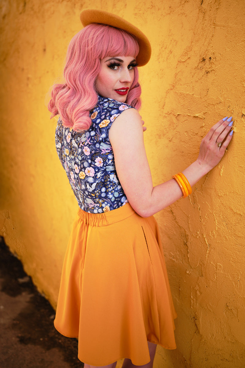 a back view of model standing in front of a yellow wall wearing mustard skater skirt