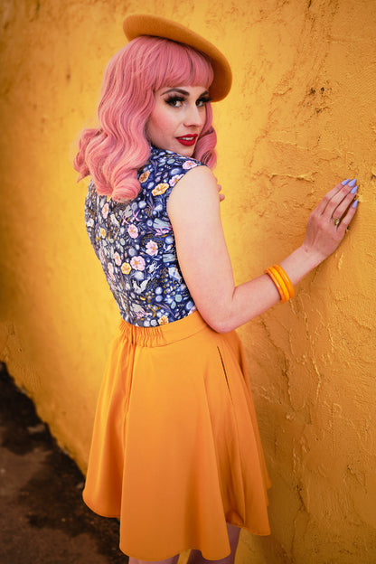 a back view of model standing in front of a yellow wall wearing mustard skater skirt