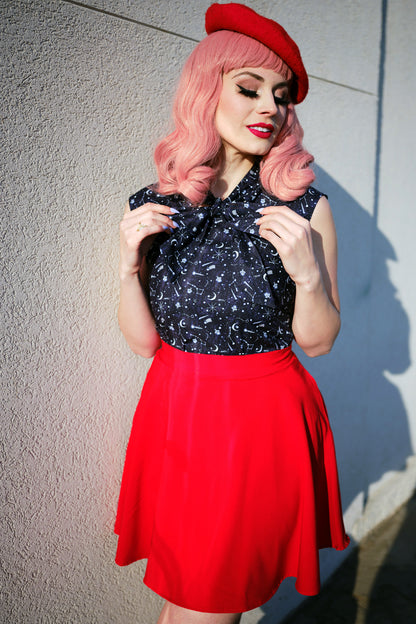a model standing in front of a wall wearing red skater skirt