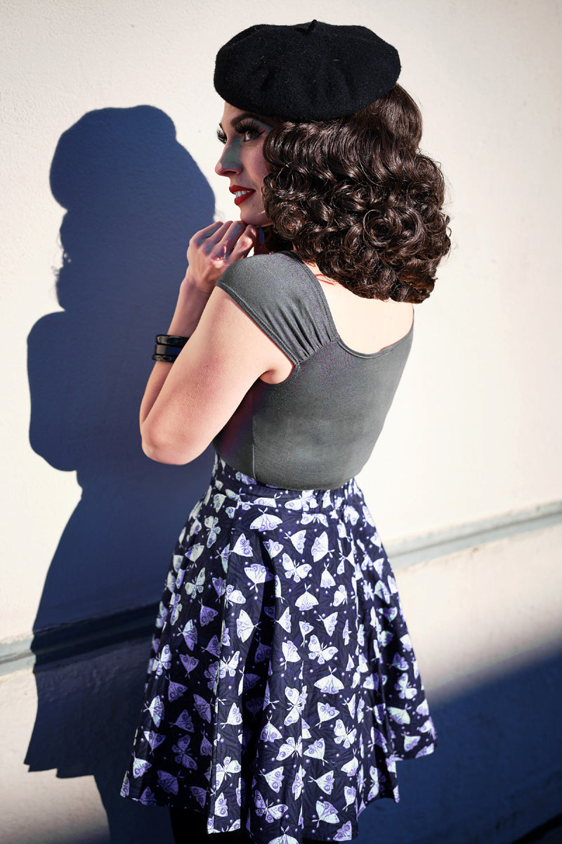side view of model standing in front of a wall wearing our Isabel top in Grey