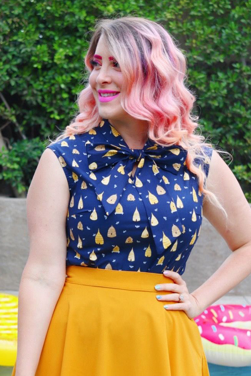 close up of model standing in front of trees wearing our beehive bow top