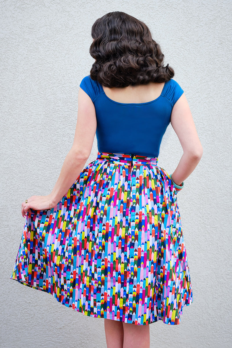 back view of model standing in front of a wall wearing our Isabel top in peacock blue