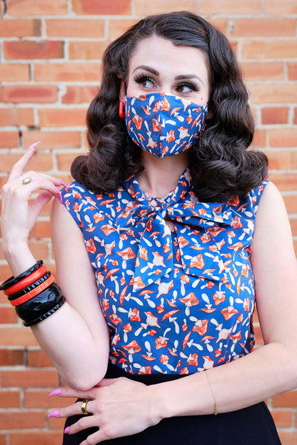 close up of model standing in front of a brick wall wearing our mushroom bow top with matching mushroom face mask